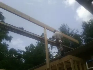 Carpenter setting a ridge beam over a new addition frame — Ice Dam Removal by Roofing Brothers in Deshler