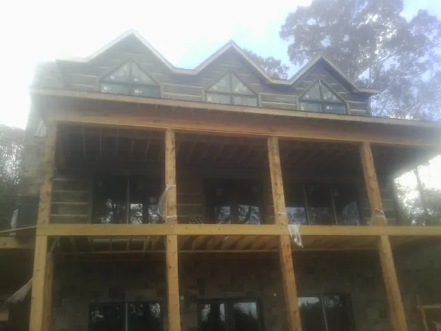 Dormers and porch framing on a large log home under construction — Roof Coating work by our crew in Deshler
