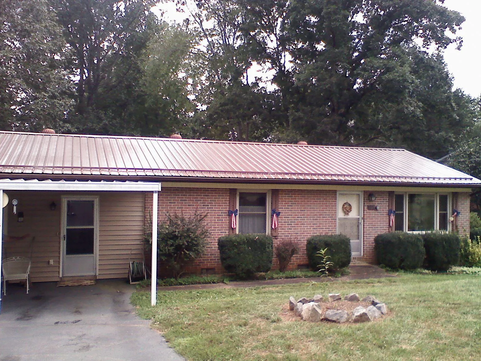 Bronze metal roof and carport on a brick ranch home — Roof Repair work by our crew in Deshler