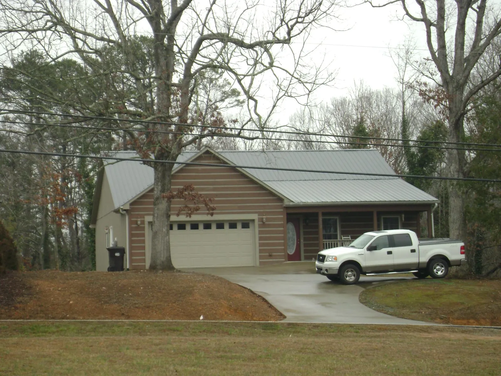 Gray metal roof on a log sided house with an attached two car garage in Deshler