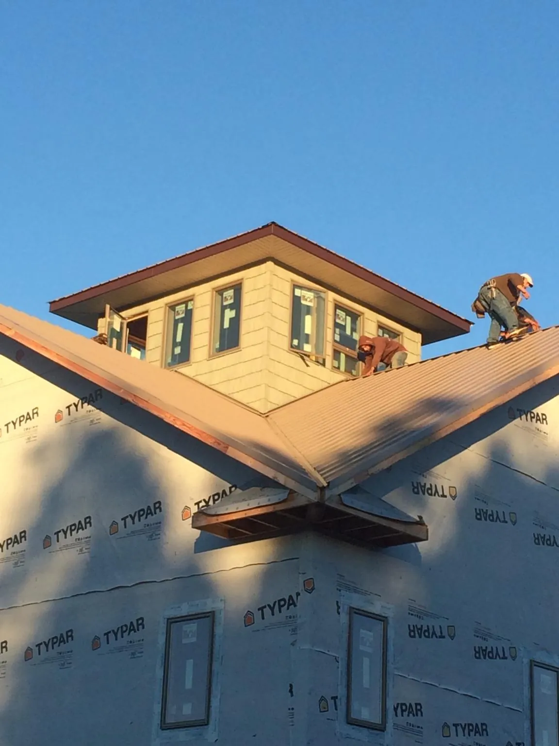 Roofers working around a rooftop cupola on a new metal roof at sunset — Roof Waterproofing in Deshler by Roofing Brothers